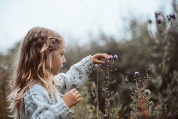 Blonde haired child plays freely outdoors with wildflowers