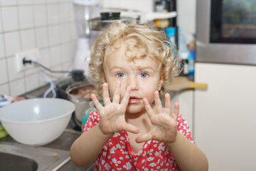 A little girl helps her mother in the kitchen with cooking.