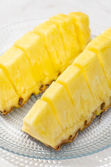 白いテーブルにガラスの器に盛ったカットパイナップルのクローズアップ