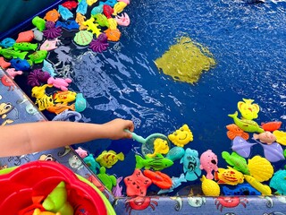 Obraz premium Hand of the child playing in fishing game. Fish toys in a water