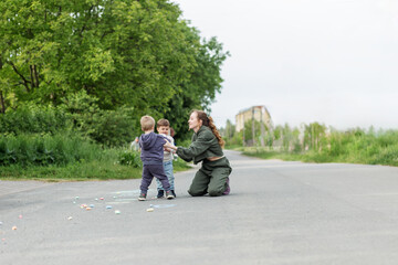 Obraz premium Mother Supervising Kids Playing with Chalk