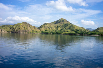 Pristine waters reflect the lush, rolling hills of Komodo Island, a serene destination in Indonesia