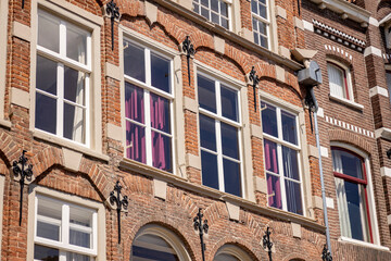 Bright frontal textured typical historic medieval exterior facades of Dutch Hanseatic city center with sharp sunlight shadows in Holland