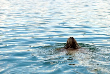 Fototapeta premium The girl bathes in the water in the river and enjoys swimming