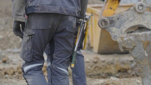 Ouvriers sur un chantier de construction avec leurs outils accroch&eacute;s &agrave; la taille. Workers on a construction site with their tools hanging from their waists.