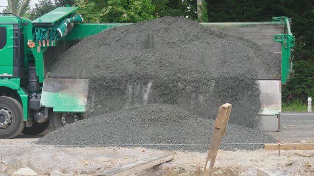 Camion benne qui d&eacute;charge du gravier sur un chantier. Dump truck unloading gravel at a construction site