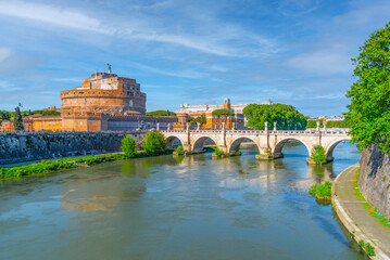 Brilliant sunshine bathes Castel Sant Angelo and the ancient Ponte Sant Angelo bridge over the Tiber River, highlighting Romes enduring architectural marvels. Rome, Italy