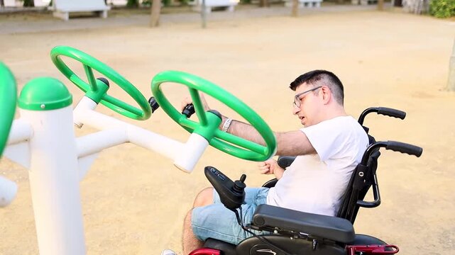 An adult man with cerebral palsy moves the wheel of a park swing for rehabilitation.Concept of people with cerebral palsy.