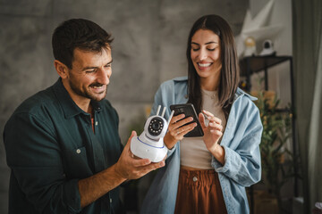 Adult couple connect cctv surveillance camera with mobile phone at home