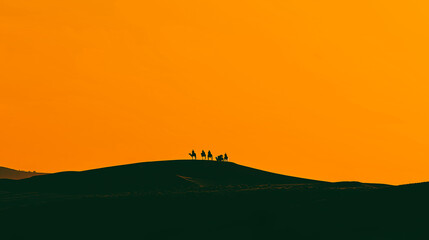 Dark silhouette of caravan with camels on a hilltop against a orange sunset sky. Travel, expedition. Middle Eastern or Central Asian desert landscape.