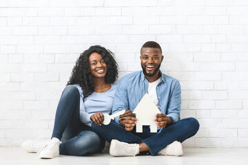 Real estate, housing and family concept. Black couple holding colorful plastic house and key over...