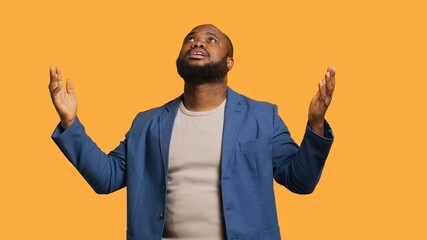 Cheerful pious african american man looking up to sky, waiting for sign from his god. Happy spiritual man doing worship hand gesturing, hoping for miracle, isolated over studio background, camera A