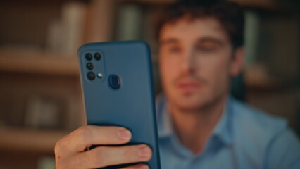 Serious guy reading sms on smartphone at night home closeup. Focused businessman