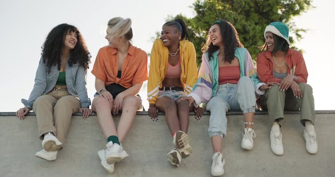Happy woman, friends and laughing at park for funny joke, meme or gossip while sitting on wall. Group of female people, smile and laugh in joy for outdoor fun, social or get together for freedom