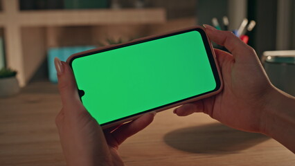 Entrepreneur video calling chroma key cellphone in dark home office close up.