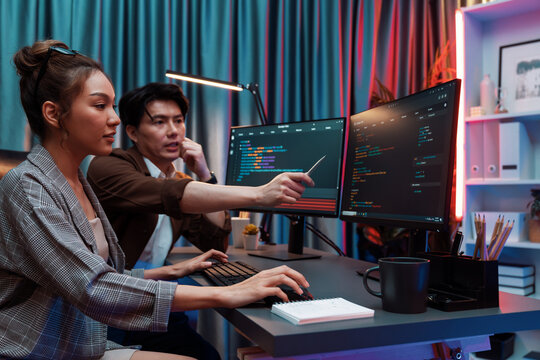 IT developers discussing with point to intelligent website development coder system running data online two screens information technology at neon light room at modern office. Infobahn.