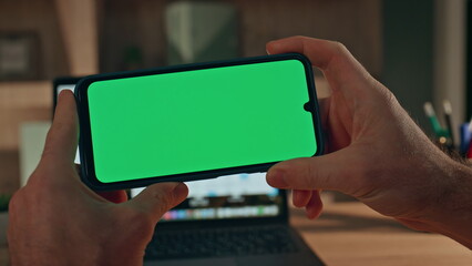 Unknown man watching green screen smartphone video in evening home close up.