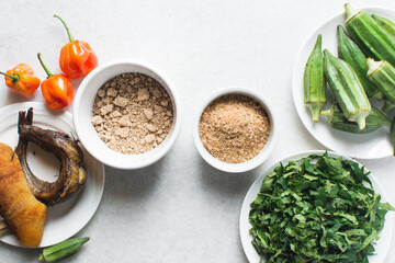 Overhead view of ingredients for making ogbono soup on a granite countertop, top view of mise en place of ingredients for making ogbono and okro soup, process of making nigerian ogbono soup