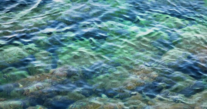 Ondeggiare del mare a riva con riflessi di luce dopo il tramonto