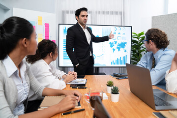 Businessman deliver business presentation with financial report data analysis or market trend show on big TV screen for strategic planing in meeting room for company future direction. Habiliment