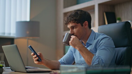 Office manager using mobile phone in morning. Closeup boss rest drinking coffee