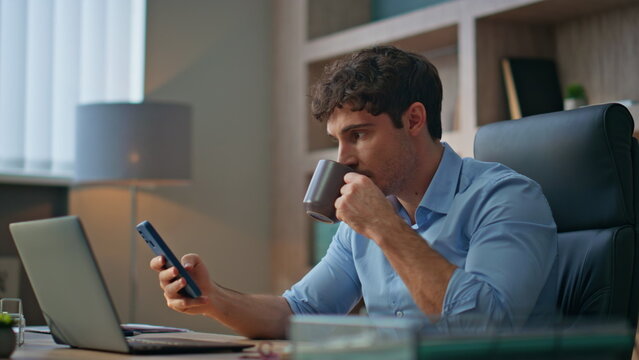 Office manager using mobile phone in morning. Closeup boss rest drinking coffee