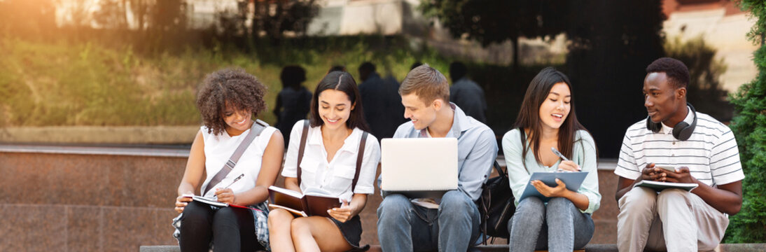 Group of happy teen high school students studying outdoors, preparing for lectures together, free space