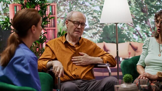 Nurse jumping to help senior man in wheelchair losing conscience during home visit, old person hyperventilating and scaring his wife. Medical assistant in panic checking the pulse. Camera A.