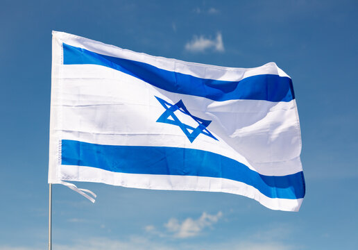 Big flag of Israel fastened on stick against background of blue sky under daylight