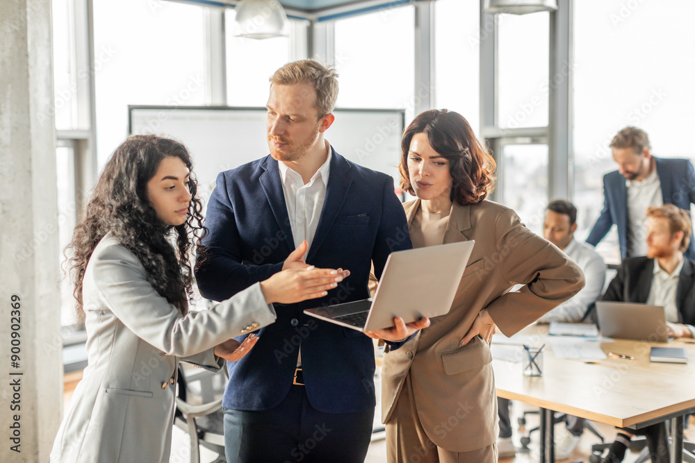 Poster three business professionals stand together in a modern office, engaged in a collaborative discussio
