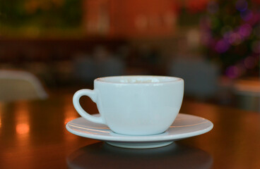 A mug of hot coffee is on the table in a coffee shop.