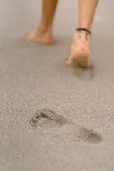 Woman walking away leaving footprints on the sand