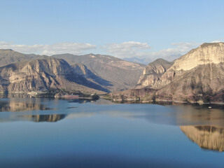 lake in the mountains during sunset and an old dam in the distance, seen  from a drone.