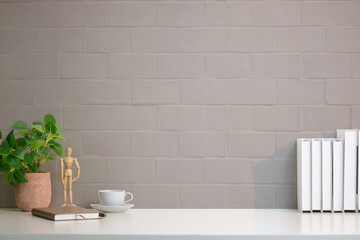 A simple and modern workspace setup featuring a clean white desk against a light gray brick wall background.