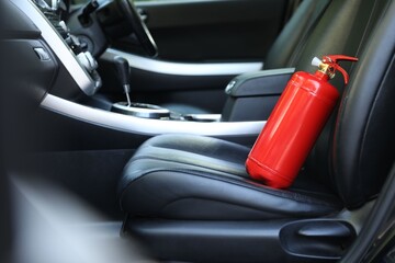Red fire extinguisher in automobile. Car safety equipment