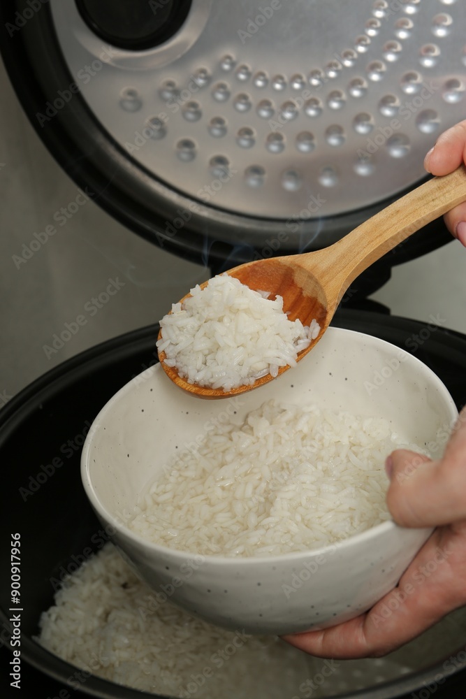 Wall mural Woman taking boiled rice into bowl on grey background, closeup