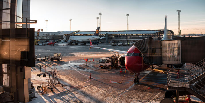 Kastrup, Denmark - 01-16-24: Early winter morning sunrise at Kastrup international airport. Cph lufthavn with Norwegian planes at the gate in frost. High definition panorama of Copenhagen airport.