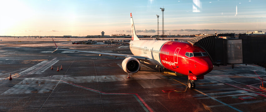 Kastrup, Denmark - 01-16-24: Early winter morning sunrise at Kastrup international airport. Cph lufthavn with Norwegian planes at the gate in frost. High definition panorama of Copenhagen airport.