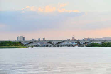 Fototapeta premium At twilight from Dadaocheng Pier, gaze across the Tamsui River to Banqiao in New Taipei City, where a mix of high-rise buildings and under-construction sites add dynamic color to the skyline.