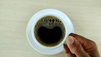Hand holding cup of black coffee and copy space for design.
