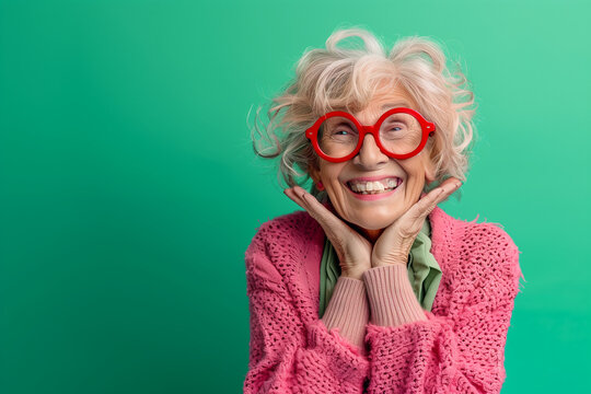 Happy smiling senior woman wearing sunglasses, green solid colorful background, image with space for text / Femme &acirc;g&eacute;e souriante et heureuse avec lunettes de soleil, fond vert, espace pour le texte