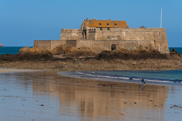 View of the Petit Be Fort on a small island and the exposed ocean floor at low tide on a sunny...