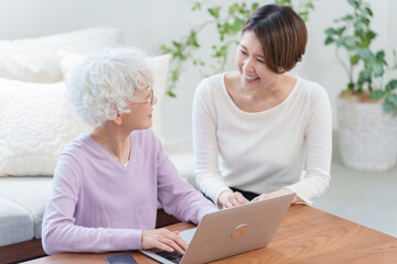 高齢者の母親にパソコンを教える娘（家族・ファミリー）