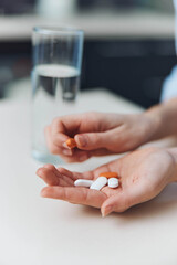Woman holding medication pills in hands with glass of water healthcare and medicine concept