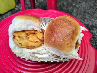 This image shows Vada Pav, a popular Indian street food. It has a spicy potato fritter inside a soft bread roll.