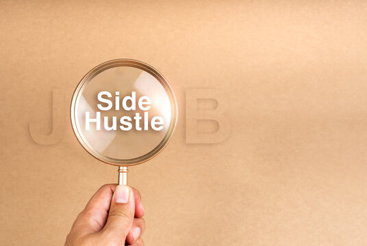 Side jobs, finding second work and searching extra income concepts. Text "Side Hustle" in gold magnifying glass in person's hand on brown recycled paper background with copy space. Business success.