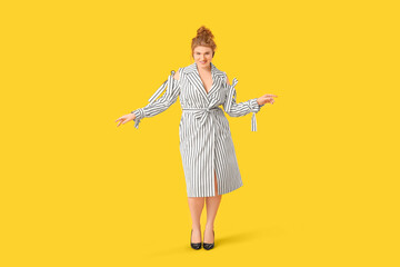 Beautiful young woman in stylish striped dress on yellow background