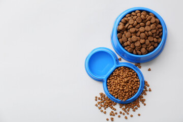 Bowls with dry pet food on white background