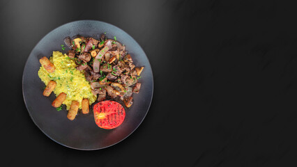 Beef steak pieces eggs and vegies on a black table top view