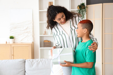 Fototapeta premium Little African-American boy with gift and his mother at home